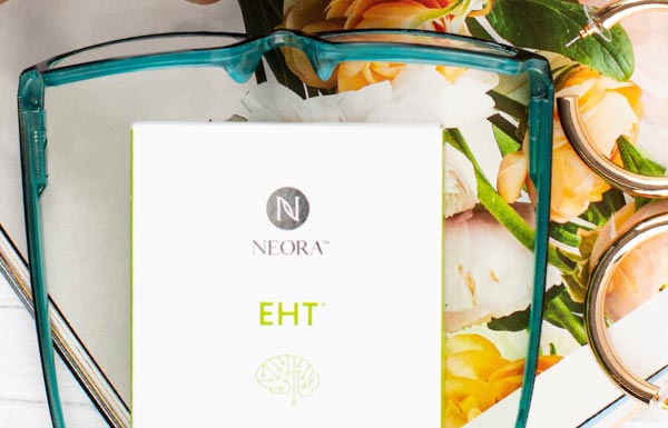 Lifestyle shot of Neora's EHT next to a pair of glasses on a tabel.